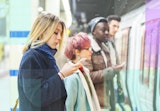 Woman looking at her phone while she waits for a train.