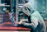 A scary person sits at a computer terminal.